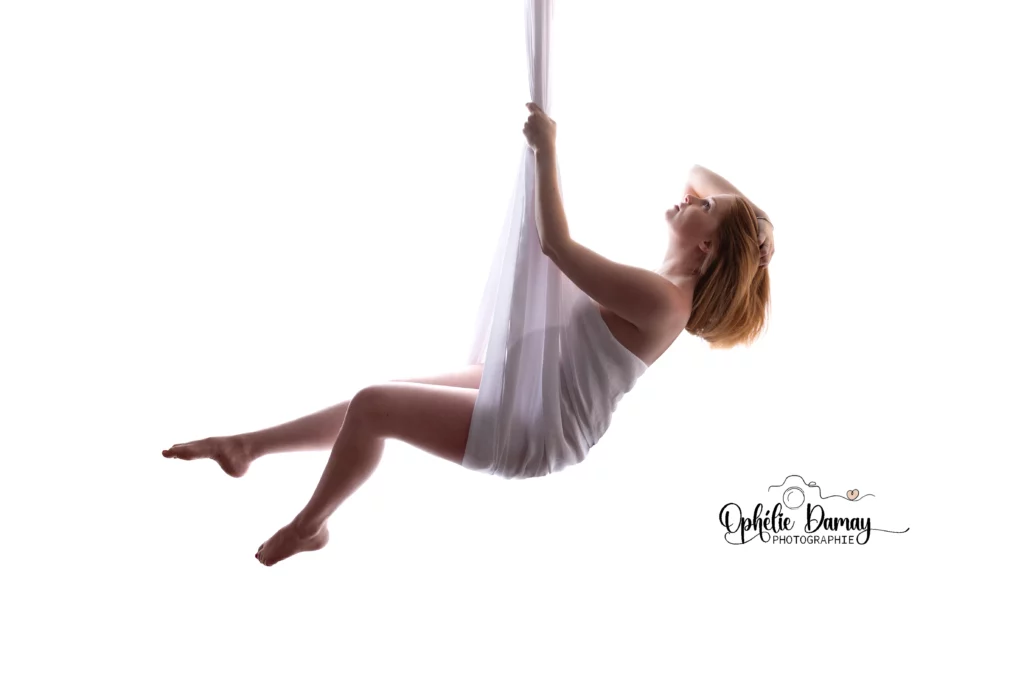 alt="Femme enceinte suspendue dans un voilage blanc, sensation de douceur et de légèreté"