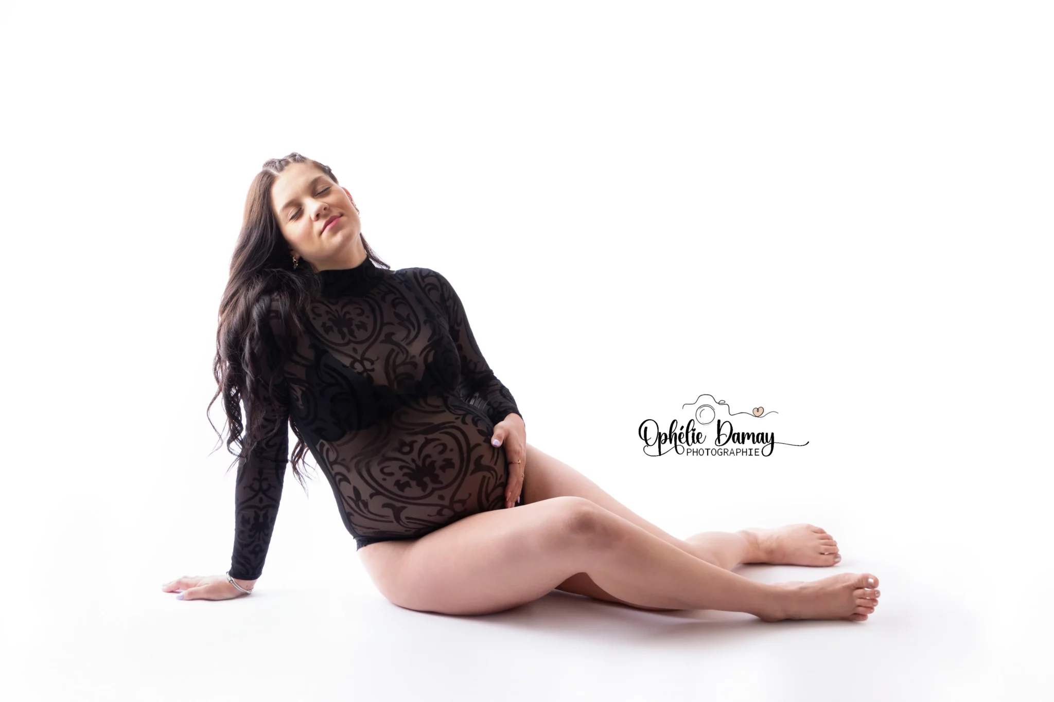 alt="Femme enceinte sur un fond blanc, les yeux fermé, entourée d'une lumière douce"