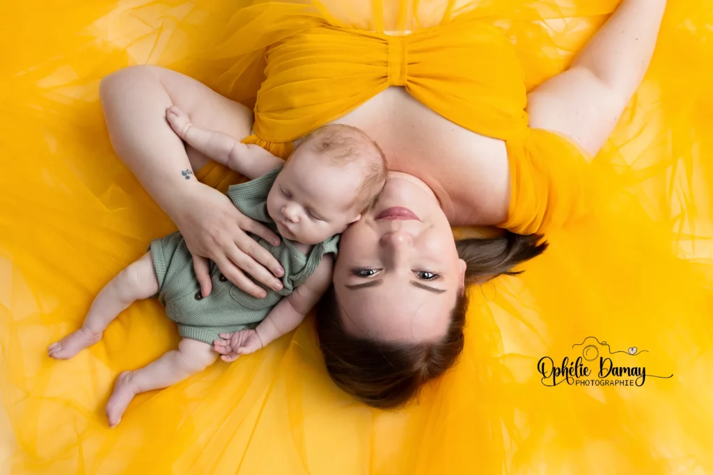 alt="Maman allongée tenant son nouveau-né avec tendresse pendant une séance naissance"