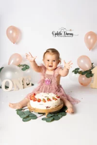 alt="Bébé fêtant ses 1 ans, qui est fière de s'être mis du gâteau partout"