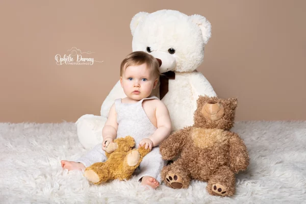 alt="Bébé entouré de peluches"