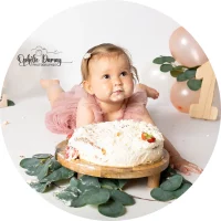 alt="Bébé allongé sur le ventre, devant un gâteau, lors d’une séance photo à Hargnies"