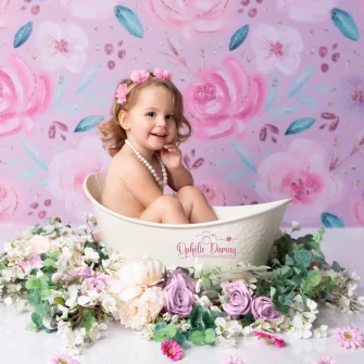 alt="Bébé dans un bain, entouré de fleurs"
