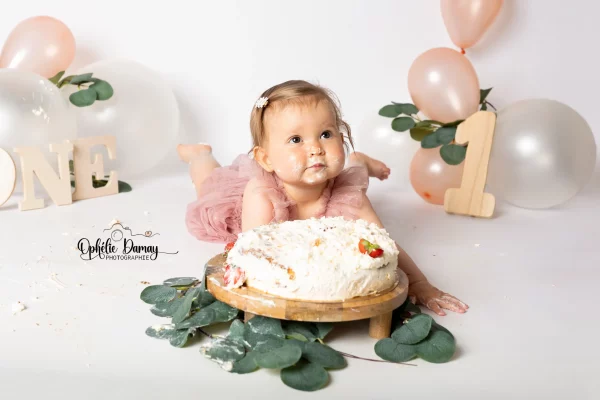 alt="bébé fêtant ses 1 an, et mangeant son gâteau tout seul en s'en mettant partout"