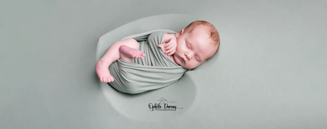 alt="Nouveau né emmailloté et déposé dans un contenant en forme de coeur"