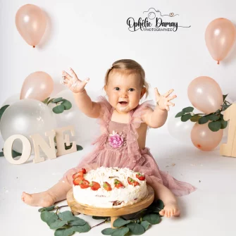 alt="Bébé fêtant ses 1 ans, qui est fière de s'être mis du gâteau partout"